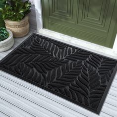 a black door mat sitting on top of a wooden floor next to a potted plant