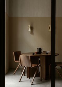 a wooden table with chairs around it and a lamp on the wall in the background