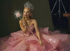 a woman in a pink dress holding a wand and wearing a tiara with stars on it