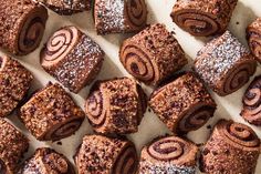 many different types of pastries on a white tray with powdered sugar sprinkled around them