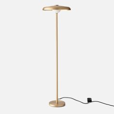 a gold floor lamp with a black cord plugged in to it's base