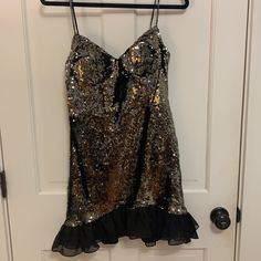 a gold and black dress hanging up on a hanger in front of a door