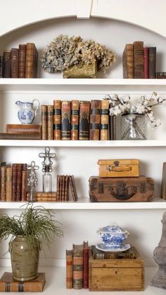 a white shelf filled with lots of books and vases on top of it's shelves