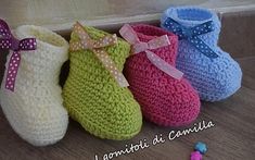 four crocheted baby booties are lined up on the floor next to each other