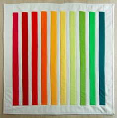 a rainbow quilt is displayed on a tablecloth with the colors of different colors in it