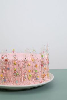 a pink frosted cake with sprinkles sitting on top of a white plate