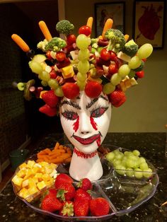 a face made out of fruit and vegetables on top of a table with other fruits