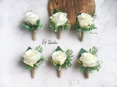 six boutonnieres with white roses and greenery