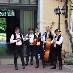 a group of men standing next to each other holding musical instruments in front of a building