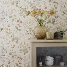 a vase filled with flowers sitting on top of a white shelf next to a wall