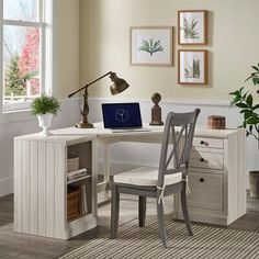 a white desk with a laptop computer on top of it next to a chair and potted plant