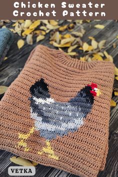 a crocheted chicken sweater is shown on a wooden surface with leaves scattered around it