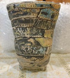 a vase sitting on top of a table next to a white cloth covered wallpaper