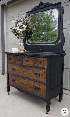 an old dresser with a mirror on top and flowers in the vase next to it