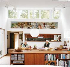 two people sitting at a table in front of a book shelf with books on it