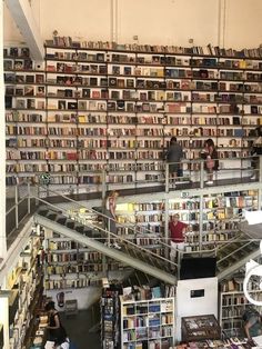 two people are standing on the stairs in front of a large amount of books