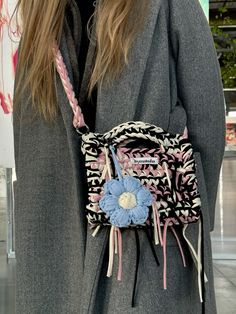 a woman wearing a gray coat holding a pink and blue purse