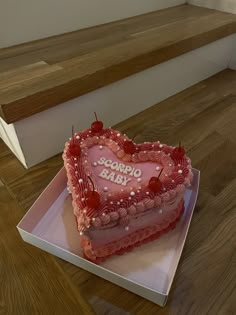 a heart shaped cake sitting on top of a white box next to some wooden stairs