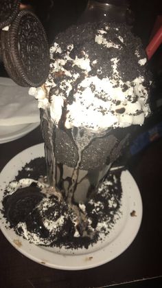 an ice cream sundae on a plate with oreo cookies and chocolate shavings