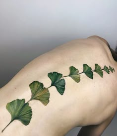 a woman's back with green leaves on it