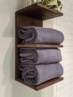 two wooden shelves holding folded towels in a bathroom