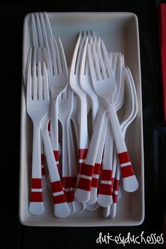 white plastic utensils with red and white stripes on them in a square tray