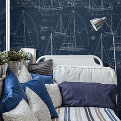 a blue and white bedroom with sailboats drawn on the wall next to bedding