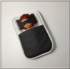 a doll in a black and white polka dot sleeping bag with blind folded over its eyes