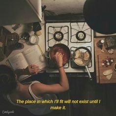 a woman reading a book in front of an oven with food on the burners