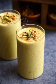 two glasses filled with food sitting on top of a blue tablecloth next to each other