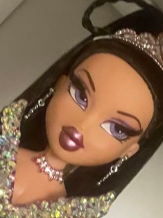 a close up of a doll wearing a tiara and holding onto a handbag