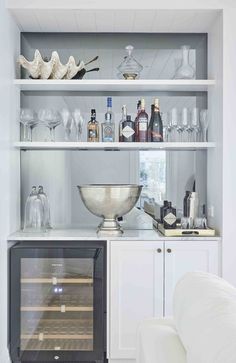 a kitchen with white cabinets and shelves filled with wine glasses, liquor bottles and other items