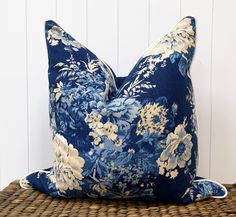 a blue floral pillow sitting on top of a wicker table