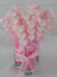 a glass vase filled with candy hearts on top of a table