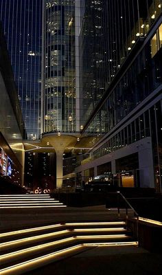 some steps lit up in the night with lights on them and buildings reflected in the windows