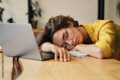 a young woman sleeping on her desk in front of a laptop