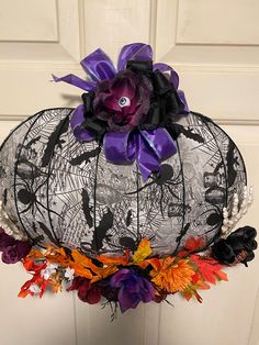 a halloween decoration hanging on the door with purple and orange flowers in front of it