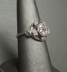 Antique Circa 1930 Constructed of 10KT White Gold with a Central 14KT White Gold Cluster of 7 Genuine Earth-Mined Old Round European cut Diamonds weighing a total of approximately 0.50 carats H-J Color; VS1-I1 Clarity (although most in the VS2-SI1 range) Cluster measuring approximately 8.2mm in diameter with 5 Genuine Earth-Mined Nearly Colorless Nearly Flawless to Slightly Included Round Single cut Smaller Accent Diamonds weighing a total of approximately 0.08 carats F-G Color; VVS1-SI1 Clarity Vintage Silver Diamond Ring Stamped 14k, Vintage White Gold Diamond Ring Stamped 14k, Vintage White Gold Diamond Ring 14k, Antique Diamond White Cluster Ring For Formal Occasions, Vintage Hallmarked Diamond White Diamond Ring, Classic Hallmarked Cluster Ring With Round Cut, Vintage Platinum Rings Stamped 14k, Estate Style White Gold Diamond Ring For Formal Occasions, Vintage Platinum Ring For Formal Occasions