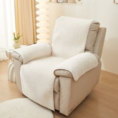 a white recliner chair sitting on top of a hard wood floor next to a window