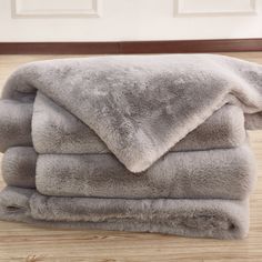 a pile of gray blankets sitting on top of a wooden floor next to a white door