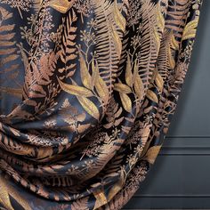 a black and gold leaf print fabric with metallic foil on the bottom, in front of a blue door