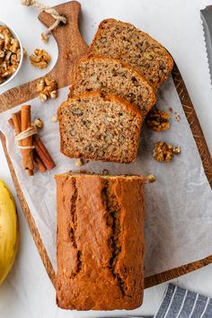 sliced loaf of banana nut bread sitting on top of a cutting board next to two bananas