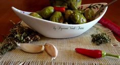 a bowl filled with green peppers next to garlic and red pepper on a tablecloth