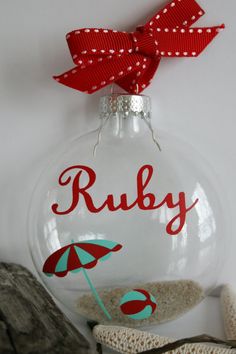 a glass ornament with a red ribbon and umbrella on it that says ruby