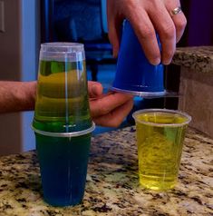 a person is pouring colored liquid into cups