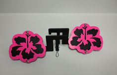 two pink and black flower shaped magnets sitting on top of a white table next to each other