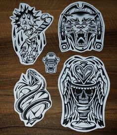 four stickers with different designs on them sitting on top of a wooden table next to each other