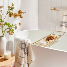 a bathtub with towels and flowers in it next to a vase filled with flowers