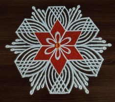 a red and white flower on a wooden surface with some lines in the center that make it look like an ornament