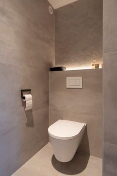 a white toilet sitting in a bathroom next to a roll of toilet paper on the wall